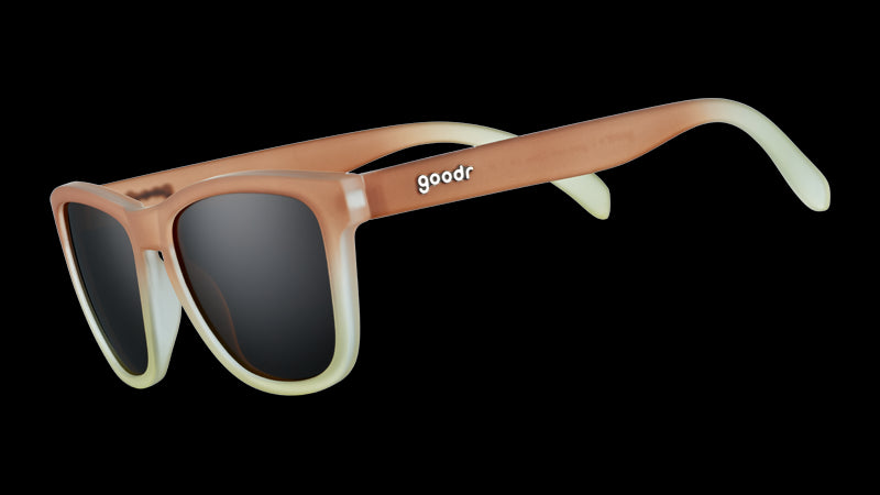 Dreiviertelansicht einer quadratischen Sonnenbrille mit Rahmen mit braunem bis weißem Farbverlauf und braunen, nicht reflektierenden Gläsern.