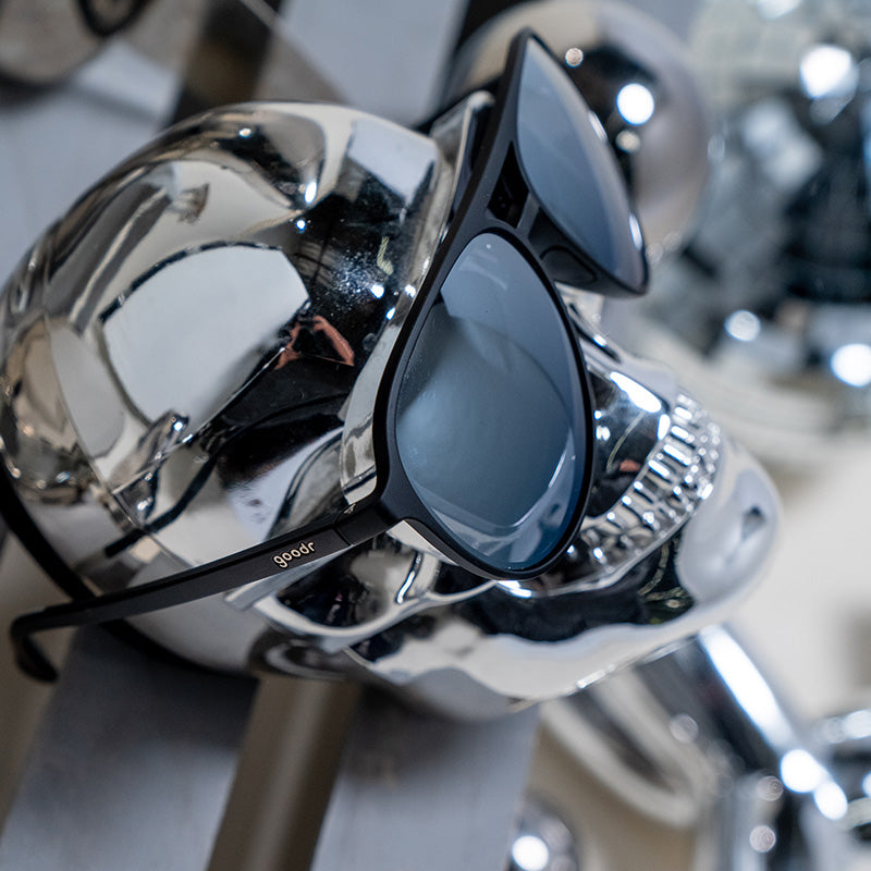 Seitenansicht einer schwarzen und verchromten Piloten-Sonnenbrille auf einem verchromten Schädel.